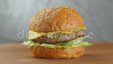 汉堡包在木板上旋转. 一个汉堡和一个<strong>切丁</strong>色拉奶酪和西红柿围绕着一个灰色的